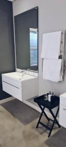 a white bathroom with a sink and a table at Cottage in Sandton in Johannesburg