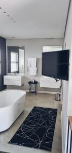 a large bathroom with a tub and a tv at Cottage in Sandton in Johannesburg
