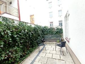una panchina seduta su un patio accanto a una siepe verde di Apartments Captain Morgan Prague a Praga