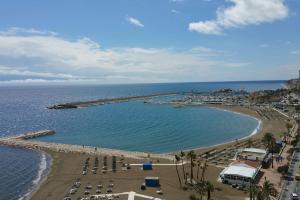 widok na plażę z kilkoma krzesłami i wodą w obiekcie Seafront apartment with open-air heated pool w mieście Fuengirola