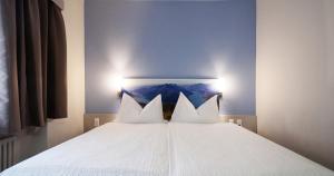 a bed with white sheets and two pillows at Acquarello Swiss Quality Hotel in Lugano