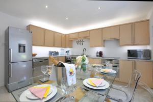 cocina con mesa de cristal y nevera de acero inoxidable en Spacious 4BR City Centre Apartment w/ Free Parking, en Edimburgo