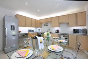 a kitchen with a glass table and a stainless steel refrigerator at Spacious 4BR City Centre Apartment w/ Free Parking in Edinburgh