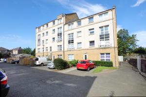 un coche rojo estacionado en un estacionamiento frente a un edificio en Spacious 4BR City Centre Apartment w/ Free Parking, en Edimburgo