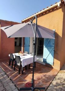 uma mesa com um guarda-chuva branco num pátio em Au soleil, marcher vers la plage em Torreilles