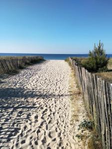 una playa de arena junto a una valla de madera en Au soleil, marcher vers la plage en Torreilles