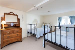two beds in a bedroom with a mirror and a dresser at Honey Cottage in Stow on the Wold