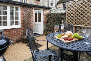 una mesa con una bandeja de frutas y copas de vino en Honey Cottage, en Stow on the Wold