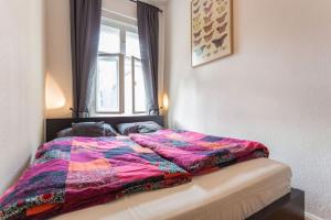 a bed with a colorful comforter in a bedroom at Zentrale Altbauwohnung im Helmholtzkiez in Berlin