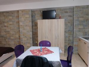 una camera con tavolo con sedie viola e televisore di Porto e MARE a Bisceglie
