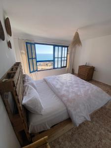 una camera da letto con un grande letto con una grande finestra di Sable beach surf camp taghazout a Taghazout
