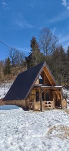 Cabaña de madera con techo negro en la nieve en Vikendica IVA, en Pale