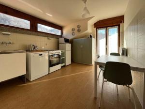 una cocina con electrodomésticos blancos, mesa y sillas en Appartamento Ai Rododendri, en Pray
