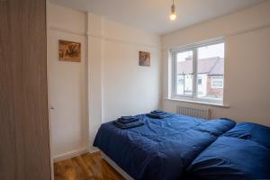 a bedroom with a blue bed and a window at Cheerful and modern 3 BDR for 7 in Liverpool