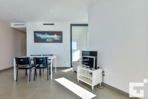 ein Wohnzimmer mit einem Tisch, Stühlen und einem TV in der Unterkunft Apartamento Bernia al Mar 8B - Grupo Turis in Calpe