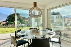 une salle à manger avec une table et des chaises et une grande fenêtre dans l'établissement Condominio Modern House, à Menaggio