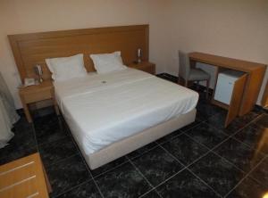 a bedroom with a large white bed and a desk at Hotel El Medina in Nouadhibou