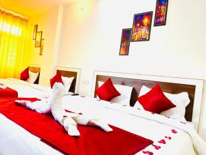a bedroom with two beds with red and white pillows at Hotel SRP in Rishīkesh