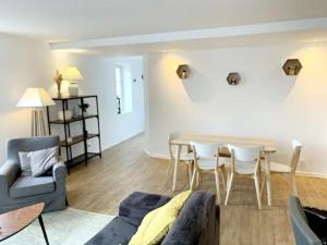 uma sala de estar com um sofá, uma mesa e cadeiras em Bel Appartement au cœur du village em Saint-Aubin