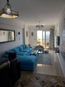 uma sala de estar com um sofá azul e uma mesa em Stunning Sea View Flat (One Bed Room)Entire Place em Alexandria