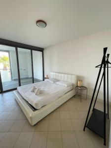 a white bed in a room with a tripod at San Lorenzo Marina Apartment in San Lorenzo al Mare