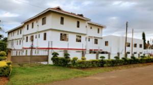 een groot wit huis met een hek ervoor bij Melvic Hotel in Kisumu