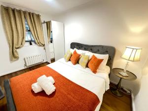 ein Schlafzimmer mit einem großen Bett mit orangefarbenen und gelben Kissen in der Unterkunft The Sherborne Residence in London