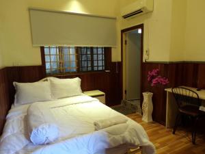 a bedroom with a bed with white sheets and a window at Dimocrata in Phnom Penh