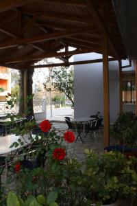a patio with red flowers and a table and chairs at Filoxenia Hotel in Volos