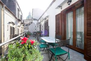 a balcony with a table and chairs and flowers at Penthouse Luxury Quattro Canti in Palermo