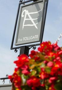 a sign on a pole next to a plant with red flowers at The Tollgate Inn in Bradford on Avon