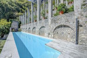 ガルニャーノにあるLimonaia Le Ravereの石壁の隣にある青い大型スイミングプール