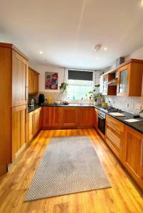 a kitchen with wooden cabinets and a rug on the floor at 2 Bedroom Apartment in Central Location in Bangor