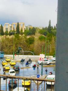 um parque de estacionamento com carros e pessoas em motocicletas em Olympian Zeus apartments em Atenas