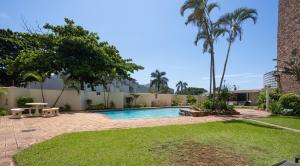 a swimming pool with a picnic table and palm trees at 24 Sea Lodge - Sea Viewing Apartment in Durban