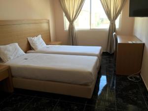 a hotel room with two beds and a window at Hotel El Medina in Nouadhibou
