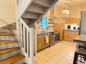 a kitchen with wooden cabinets and a staircase with a sink at Havre de paix spa proche Amboise & châteaux de la Loire in Noizay