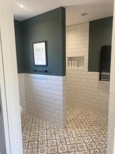 een badkamer met een betegelde douche met een bord aan de muur bij The Old Nurseries Luxury Guest Suite in Lincoln