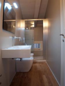 uma casa de banho com um lavatório branco e um WC. em Acquaderni Rooms em Bolonha