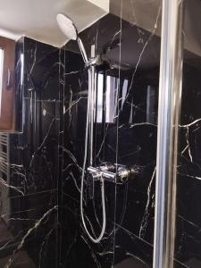 a shower in a bathroom with a black marble wall at A G Studio's Palas-Iasi in Iaşi