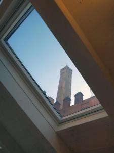 ein Fenster in einem Gebäude mit einem Uhrturm im Hintergrund in der Unterkunft Acquaderni Rooms in Bologna
