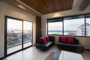 a living room with two leather chairs and large windows at Amanta Hotel Nongkhai in Nong Khai