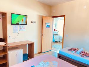 a room with two beds and a tv on the wall at Pousada Mar de Almirante in Penha