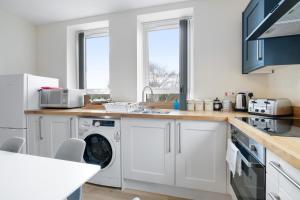 een keuken met witte kasten en een wasmachine en droger bij SPECIAL OFFER!! Wednesbury, 1& 2 Bedroom Apartments with Private Parking by 12Stay in Wednesbury