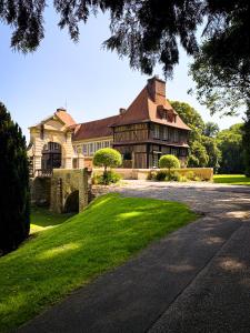 a large house with a gambrel roof and a driveway at Les Suites Château du Breuil Normandie in Le Breuil-en-Auge