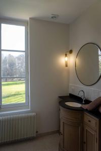 un bagno con lavandino, specchio e finestra di Les Suites Château du Breuil Normandie a Le Breuil-en-Auge