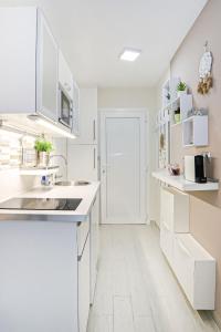 a white kitchen with white cabinets and a sink at Silver Lodge Ezüstpart Apartman in Siófok