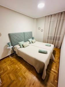 a bedroom with two beds and a wooden floor at Apartamento Oviedo Parque del Oeste in Oviedo