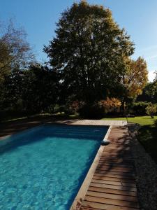 uma piscina com um passadiço de madeira ao lado de uma árvore em Douvilla em Douville