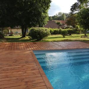 una piscina con una pasarela de madera junto a un patio en Douvilla en Douville